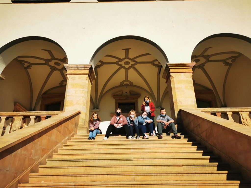 Uczniowie siedzą na schodach zabytkowego budynku
