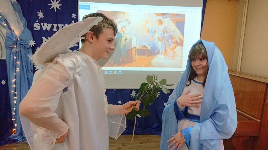 Chłopiec przebrany za anioła trzyma gałązkę